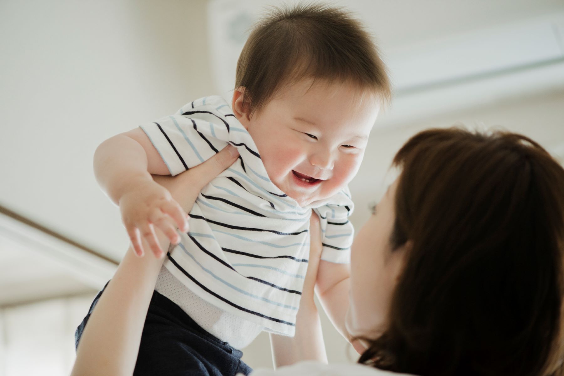 Smiling baby being lifted by mother