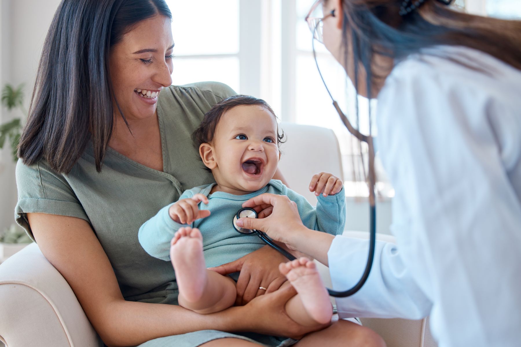 mom holding smiling baby being treated by the doctor