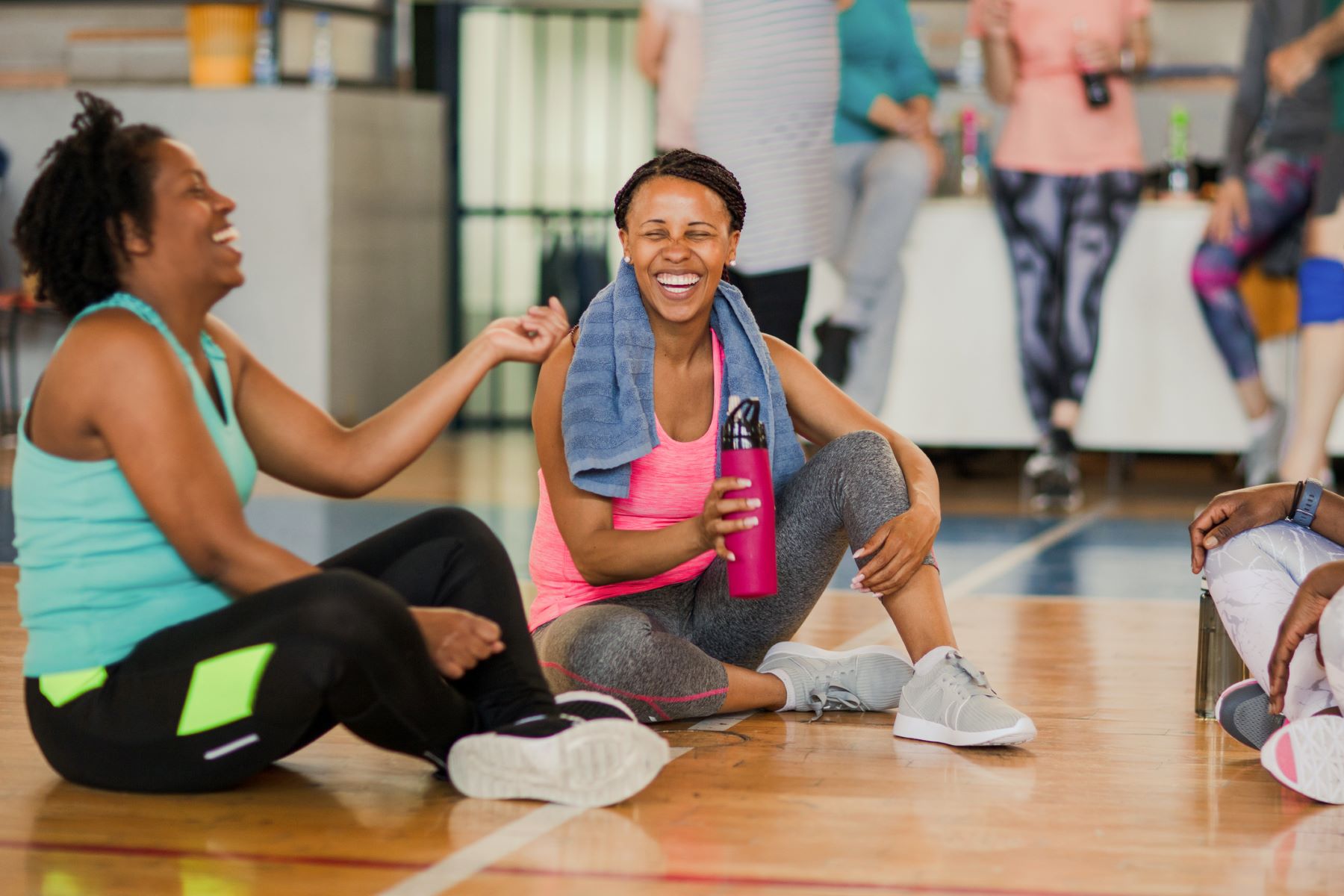 two laughing women relaxing after fitness class