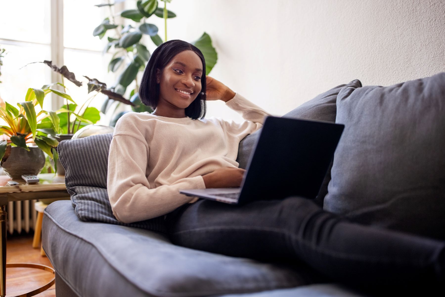 smiling young woman with a computer sitting on a sofa