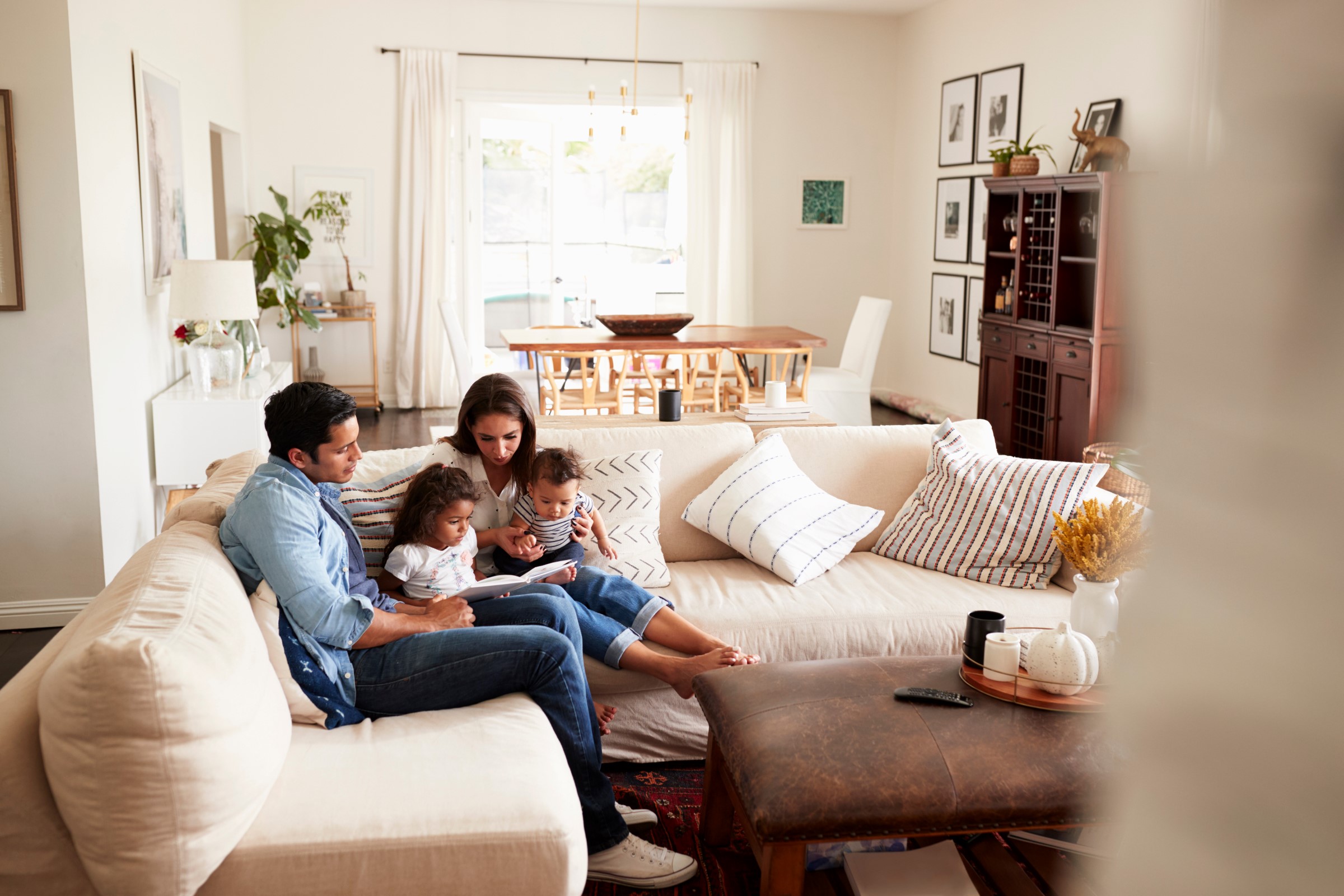 Parents reading to two young children on the sofa