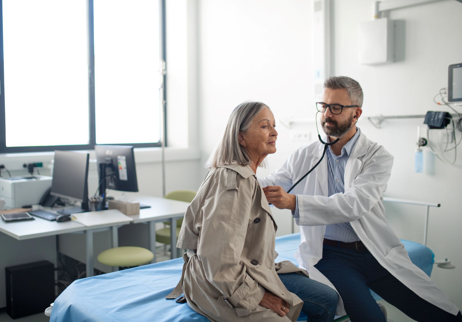 male doctor listening to his elderly female patient's heart with a stethescope